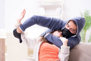 Silahlı bir adam evde genç bir kadına saldırıyor.