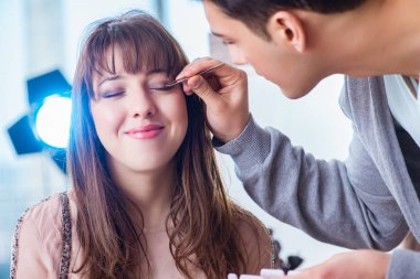 Güzellik salonunda güzel bir kadın için makyaj yapan adam.