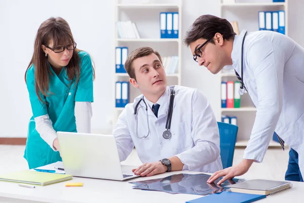 Tre läkare diskuterar skanningsresultat av röntgenbild — Stockfoto