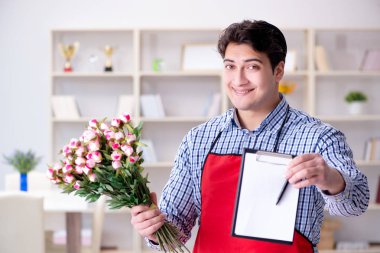 Çiçekçi asistanı bir demet çiçek veriyor.