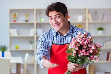 Çiçekçi asistanı bir demet çiçek veriyor.