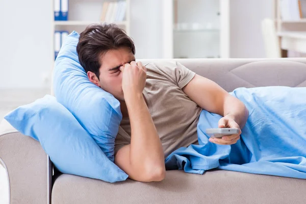 Man tittar på tv från sängen med fjärrkontroll — Stockfoto