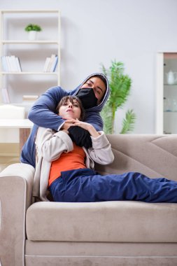 Silahlı bir adam evde genç bir kadına saldırıyor.