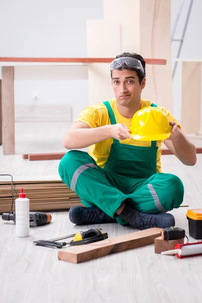Carpenter wearing yellow hardhat in contractor workshop