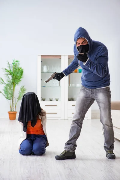 Armado homem assaltando jovem mulher em casa — Fotografia de Stock