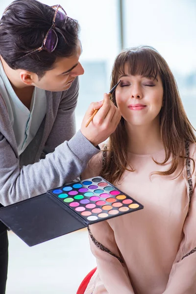 Hombre haciendo maquillaje para mujer linda en salón de belleza —  Fotos de Stock