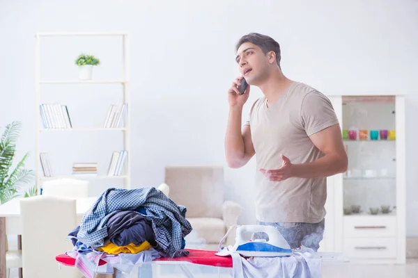 Marido desatento queimando roupas enquanto passa a ferro — Fotografia de Stock