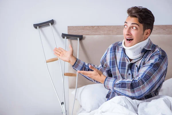 Zraněný muž doma v posteli s berlemi — Stock fotografie