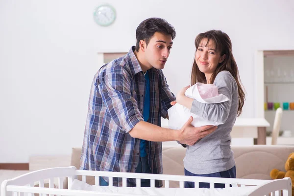 Fiatal szülők újszülött kisbabával az ágy mellett — Stock Fotó