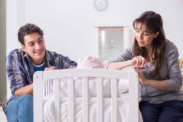 Νέοι γονείς με το νεογέννητο μωρό τους κοντά στο κρεβάτι — Φωτογραφία Αρχείου