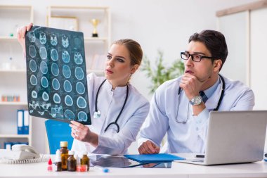 İki doktor teşhis için hastanın röntgen görüntülerini inceliyor.