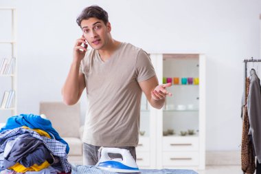 Genç adam evde çamaşır ütülüyor.