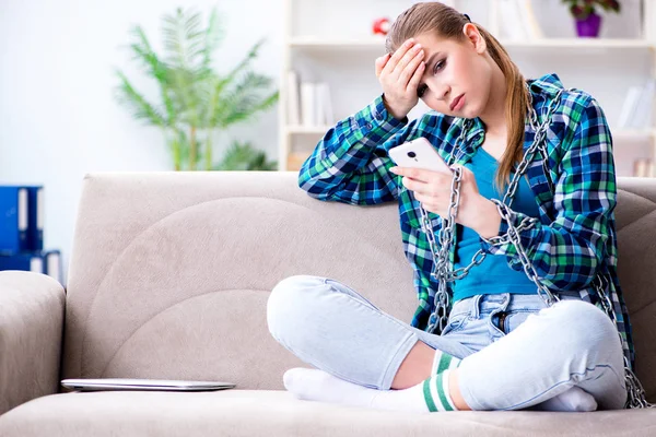 Spoutaná studentka s mobilním posezením na pohovce — Stock fotografie