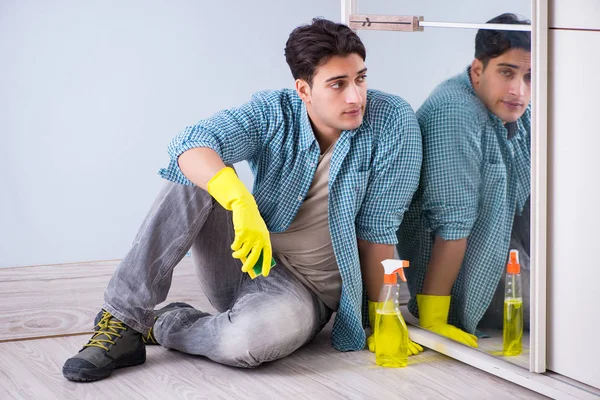 Young man cleaning mirror at home hotel — Stock Photo, Image