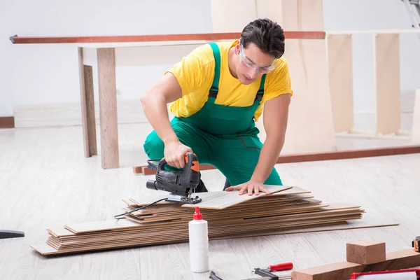 Empreiteiro que trabalha no piso de madeira laminado — Fotografia de Stock