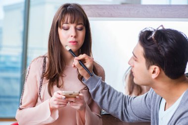 Güzellik salonunda güzel bir kadın için makyaj yapan adam.