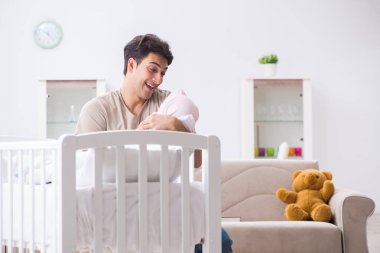 Genç baba evde yeni doğmuş bebekle eğleniyor.