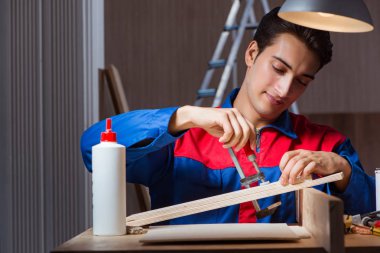 Genç adam ahşap parçaları DIY konseptinde yapıştırıyor.