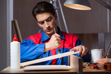 Genç adam ahşap parçaları DIY konseptinde yapıştırıyor.