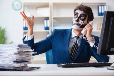 Ofiste çalışan korkunç maskeli bir iş adamı.