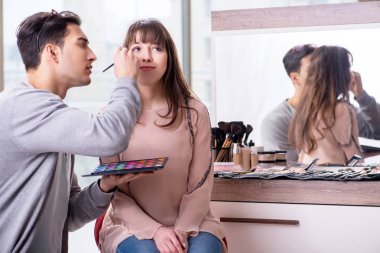Güzellik salonunda güzel bir kadın için makyaj yapan adam.