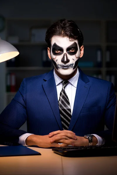 Podnikatel s děsivou obličejovou maskou pracuje pozdě v úřadu — Stock fotografie