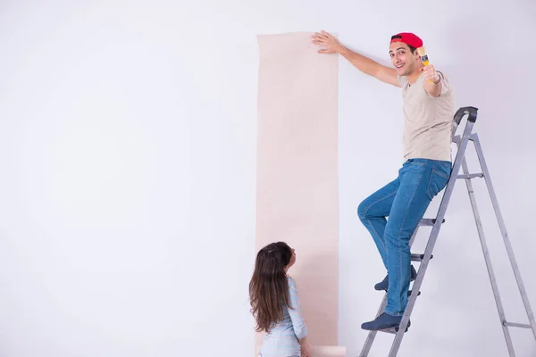 Família jovem fazendo renovação em casa com novo papel de parede — Fotografia de Stock
