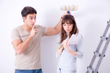 Genç bir aile evlerinde tadilat yapıyor. Duvarları boyuyor.