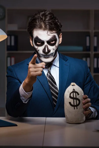 Businessman with scary face mask working late in office — Stock Photo, Image