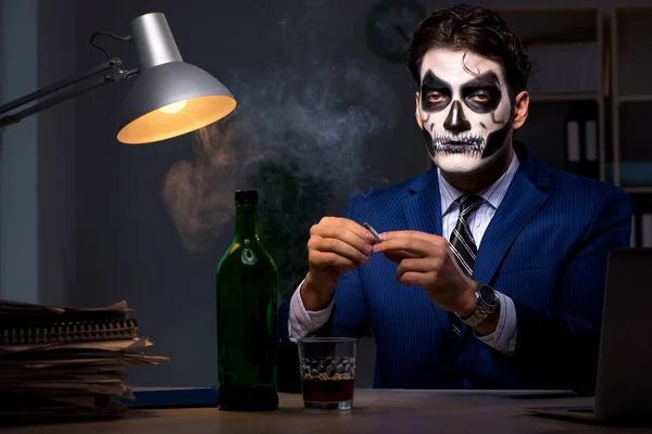 Бизнесмен в страшной маске работает допоздна в офисе — стоковое фото