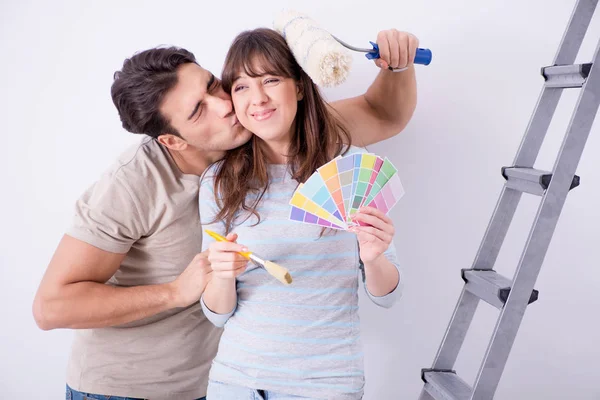 Jovem família fazendo renovação em casa - paredes de pintura — Fotografia de Stock