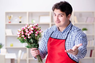 Çiçekçi asistanı bir demet çiçek veriyor.