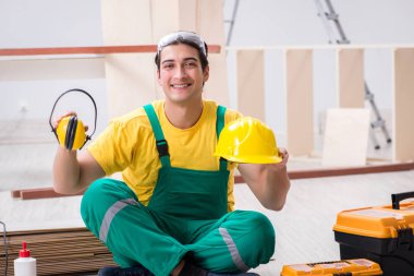 Müteahhit atölyesinde sarı şapka takan marangoz.