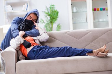 Silahlı bir adam evde genç bir kadına saldırıyor.