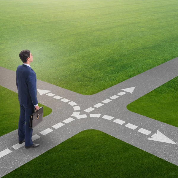 Young businessman at crossroads in uncertainty concept — Stock Photo, Image