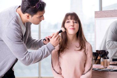 Güzellik salonunda güzel bir kadın için makyaj yapan adam.