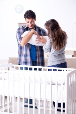 Yatağın yanında yeni doğmuş bebekleri olan genç ebeveynler.