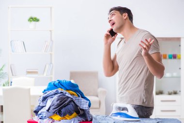 Genç adam evde çamaşır ütülüyor.