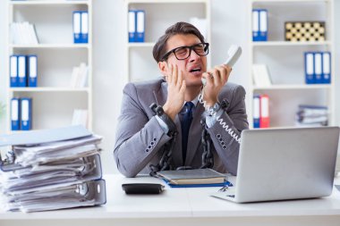 Ofis masasına zincirlenmiş meşgul bir çalışan.