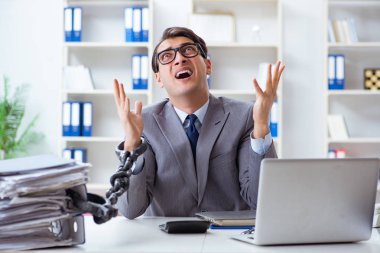 Ofis masasına zincirlenmiş meşgul bir çalışan.
