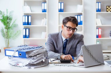 Ofis masasına zincirlenmiş meşgul bir çalışan.