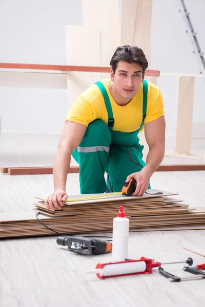 Empreiteiro que trabalha no piso de madeira laminado — Fotografia de Stock