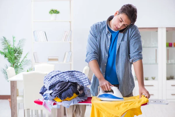 Joven marido haciendo planchado de ropa en casa — Foto de Stock