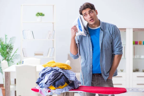 Joven marido haciendo planchado de ropa en casa — Foto de Stock