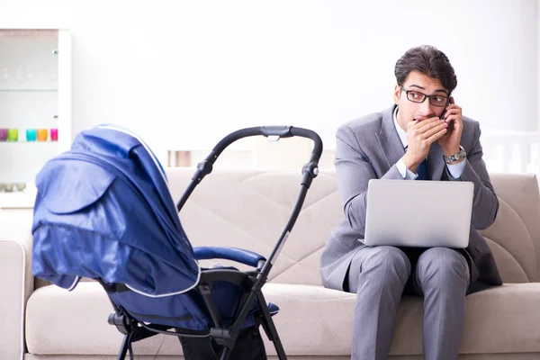 Businessman looking after newborn baby at home and teleworking — Stock Photo, Image