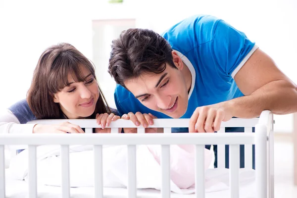 Happy young family at baby bed cot — Stock Photo, Image