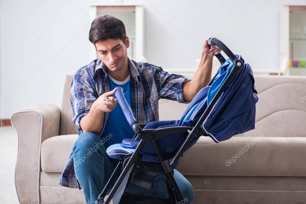 Young father assembling baby pram at home