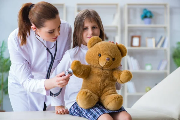 Mulher médica examinando pouco bonito menina com urso de brinquedo — Fotografia de Stock