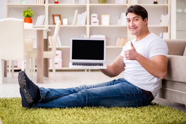 Uomo che lavora sul computer portatile a casa sul pavimento del tappeto — Foto Stock