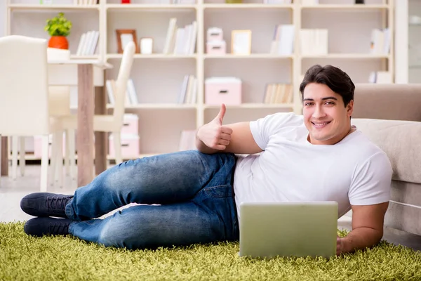 Man werkt op laptop thuis op tapijt vloer — Stockfoto